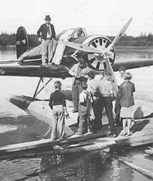 The Wiley Post-Will Rogers airplane refueling on the Chena River. Will Rogers and Wiley Post are signing autographs for the Spencer family children. August 15, 1935 Photo of the Wiley Post-Will Rogers airplane refueling on the Chena River. Will Rogers and Wiley Post are signing autographs for the Spencer family children gathered on the dock. August 15, 1935