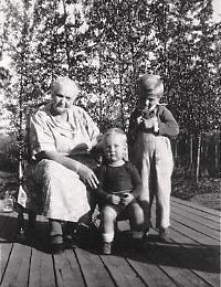 Louisa Buzby and grandchildren Robbie Gleason and Sammy Buzby sitting outside on the porch.