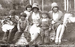 Black and white photo of Bessie Spencer and her children, sitting in a row on a large log at their Alaska homestead, 1929