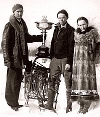 Photo of Elton presenting dog sled trophy to Bob Buzby, with Tiny standing at the right.
